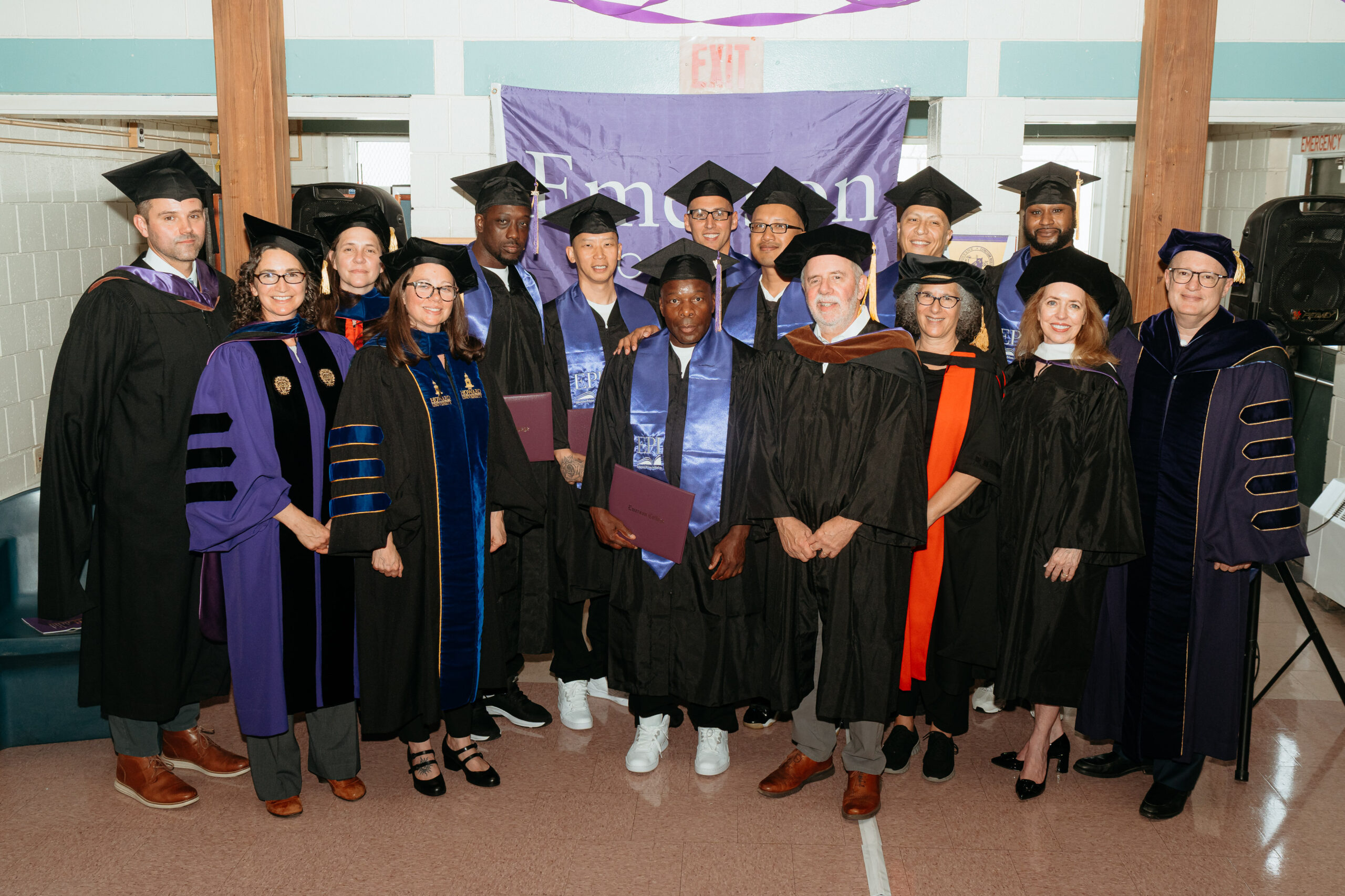 The graduating EPI cohort smiling for a photo alongside EPI and College leadership, while holding their degree covers