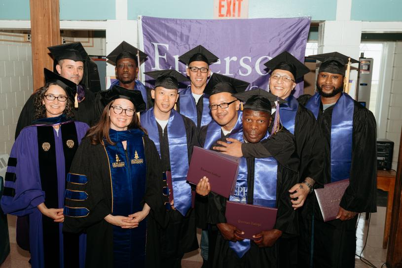 The graduating EPI cohort smiling for a photo alongside EPI program leaders, while holding their degree covers